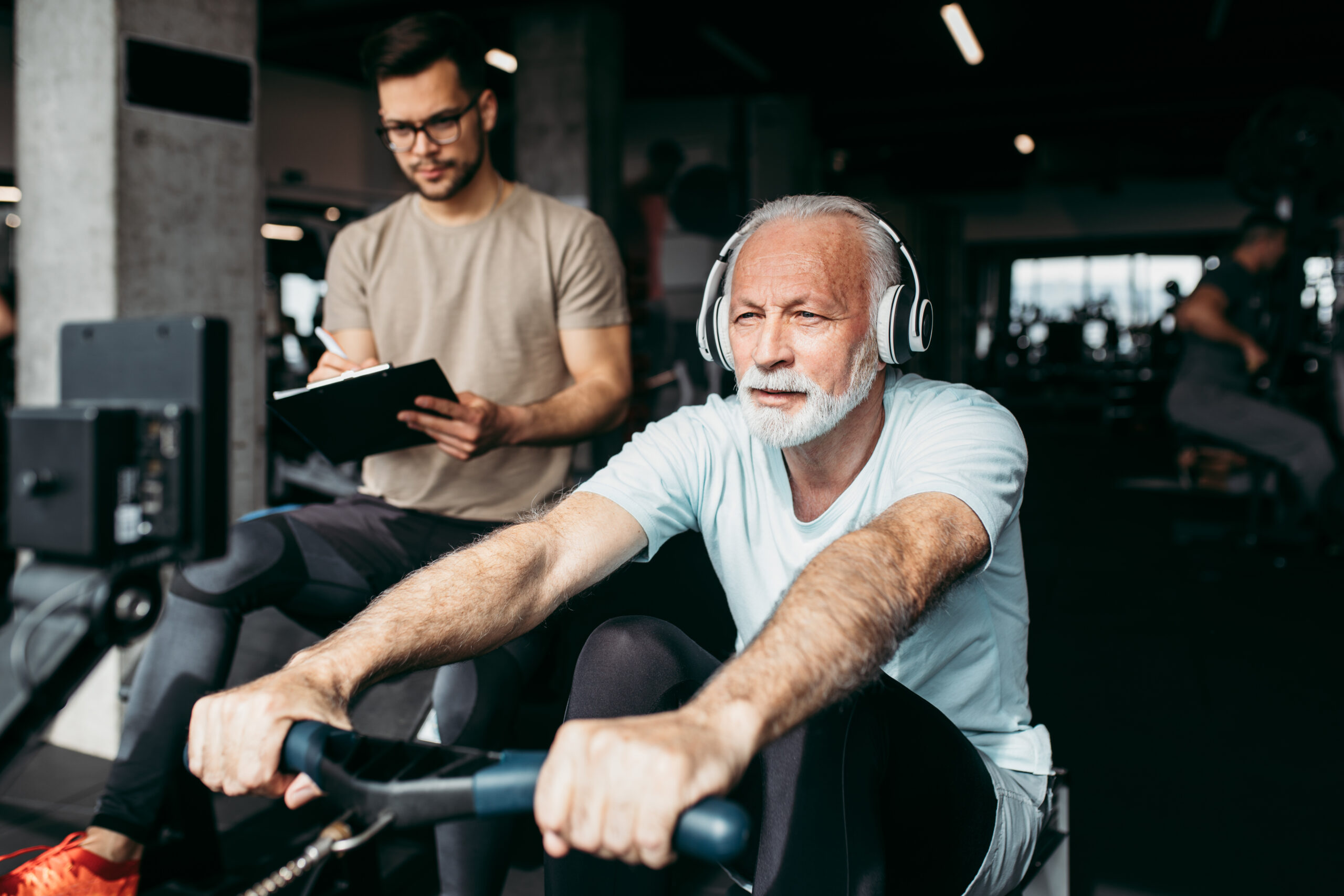 Senior Man Exercising In Gym With His Personal Trainer.